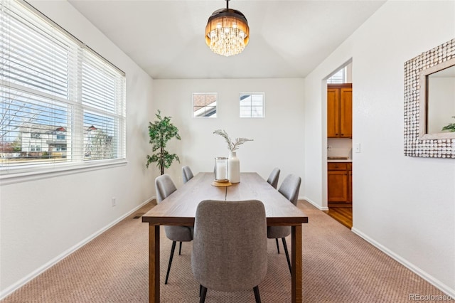 dining area with baseboards, plenty of natural light, and light carpet