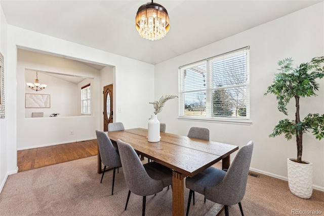 carpeted dining room featuring a notable chandelier, a healthy amount of sunlight, visible vents, and baseboards