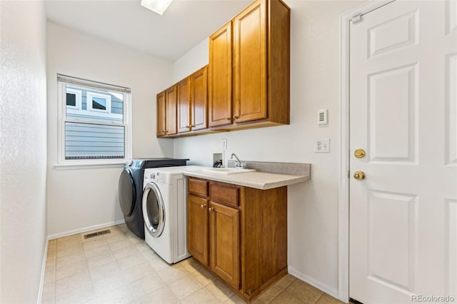 laundry area with visible vents, a sink, cabinet space, baseboards, and washing machine and clothes dryer