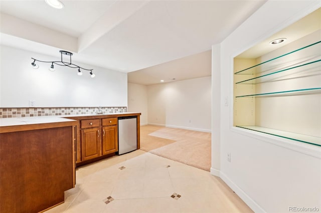 kitchen with backsplash, refrigerator, brown cabinetry, light tile patterned floors, and light colored carpet