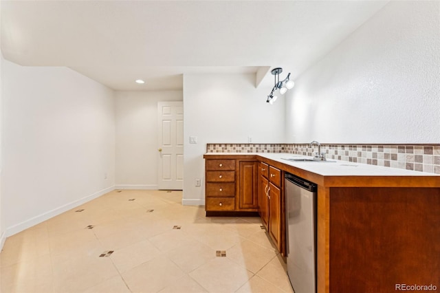 kitchen featuring backsplash, baseboards, light countertops, brown cabinetry, and a sink