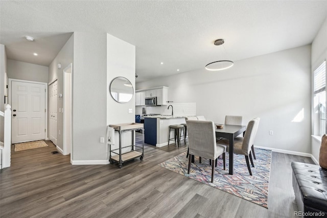 dining area featuring a textured ceiling, baseboards, wood finished floors, and recessed lighting