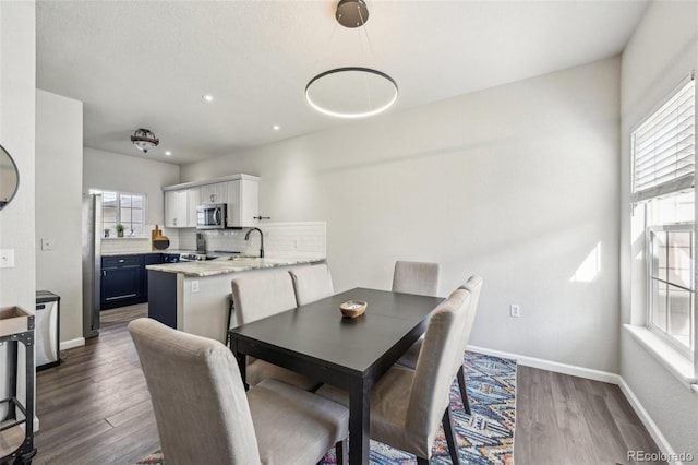 dining space with plenty of natural light, baseboards, and dark wood-style flooring