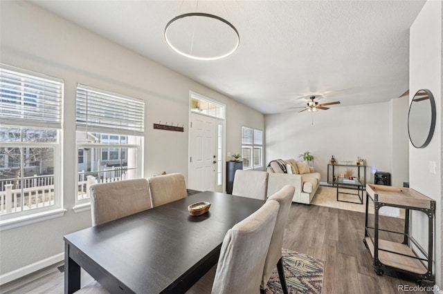 dining space with a textured ceiling, wood finished floors, a ceiling fan, and baseboards