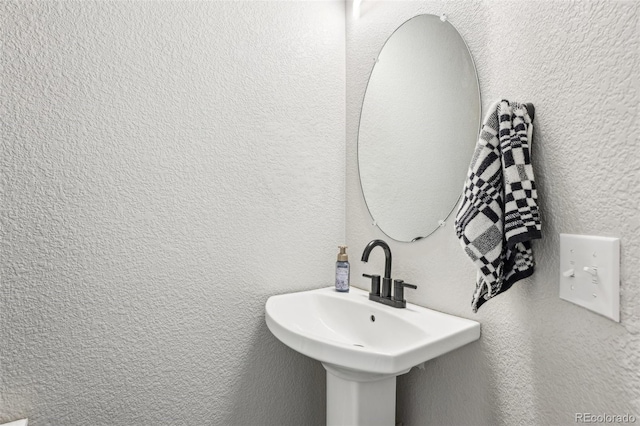 bathroom with a textured wall and a sink