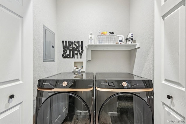 washroom featuring a textured wall, laundry area, washer and clothes dryer, and electric panel