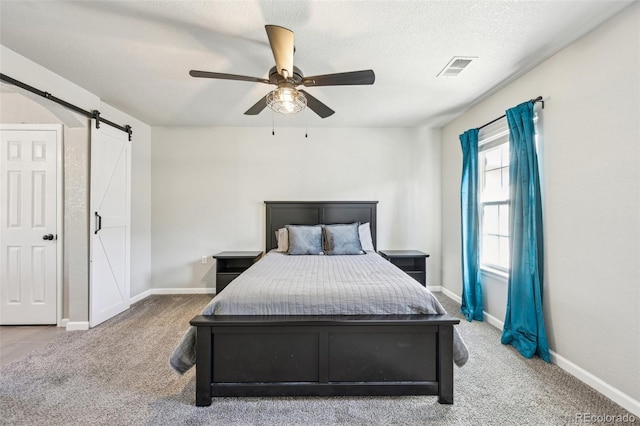 bedroom with carpet, a barn door, a ceiling fan, a textured ceiling, and baseboards