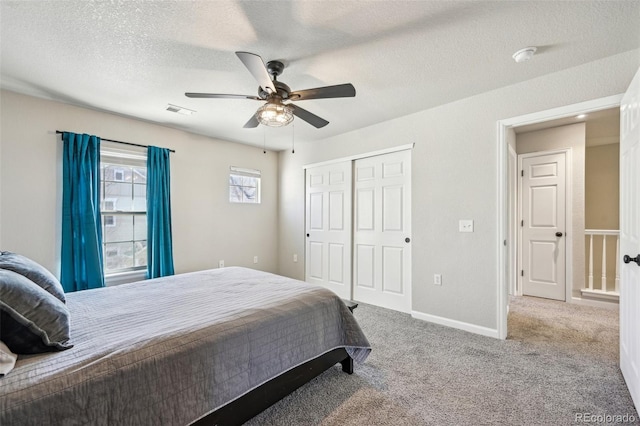 bedroom featuring baseboards, visible vents, a textured ceiling, carpet floors, and a closet