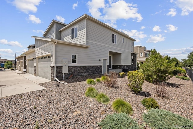 23633 E 5th Dr, Aurora, CO 80018 - view of side of home with concrete driveway, a garage, and stone siding
