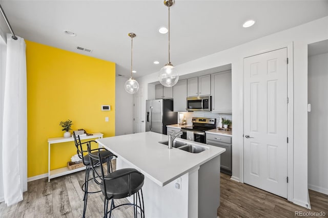 23633 E 5th Dr, Aurora, CO 80018 - kitchen featuring appliances with stainless steel finishes, gray cabinets, wood finished floors, a center island with sink, and recessed lighting