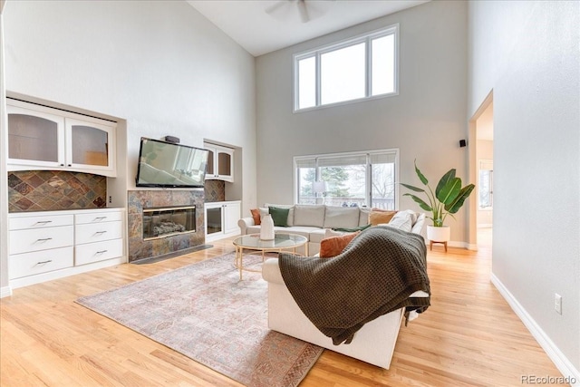 58 Rogers Ct, Golden, CO 80401 - living room featuring high vaulted ceiling, light wood-style flooring, a tile fireplace, and baseboards