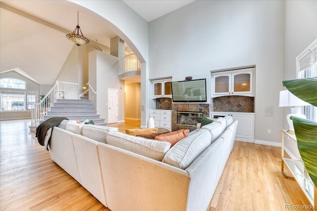 58 Rogers Ct, Golden, CO 80401 - living room featuring high vaulted ceiling, stairs, light wood finished floors, arched walkways, and a stone fireplace
