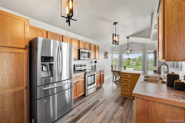 8617 W 17th Street Dr, Greeley, CO 80634 - kitchen with appliances with stainless steel finishes, a sink, a chandelier, wood finished floors, and vaulted ceiling