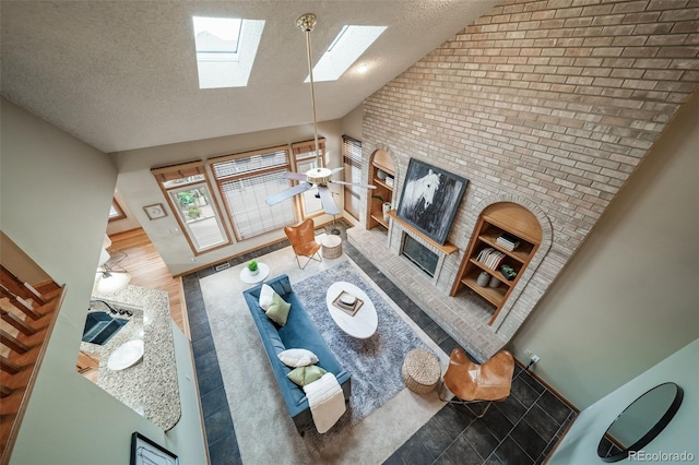 living room with high vaulted ceiling, a skylight, ceiling fan, a textured ceiling, and wood-type flooring