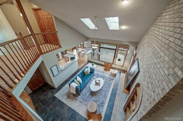 living room with a skylight, high vaulted ceiling, dark tile patterned flooring, and a textured ceiling