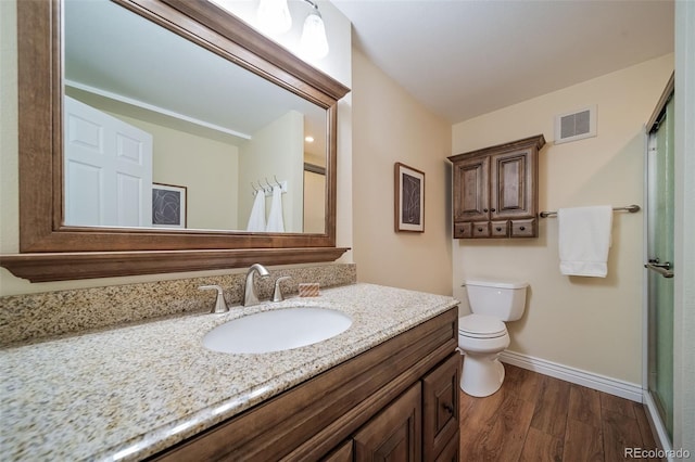 bathroom with hardwood / wood-style floors, vanity, toilet, and an enclosed shower