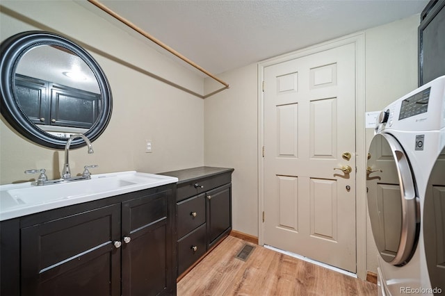 washroom with cabinets, light hardwood / wood-style floors, washer / dryer, and sink