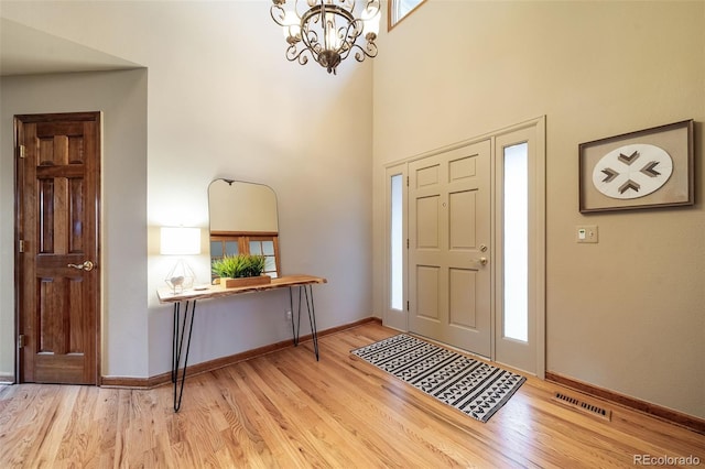 entryway with a high ceiling, an inviting chandelier, and light hardwood / wood-style flooring