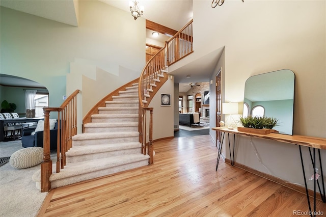 stairs with a fireplace, a towering ceiling, hardwood / wood-style flooring, and a wealth of natural light