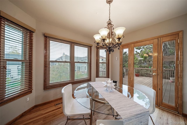 dining space with a notable chandelier, plenty of natural light, and light hardwood / wood-style floors