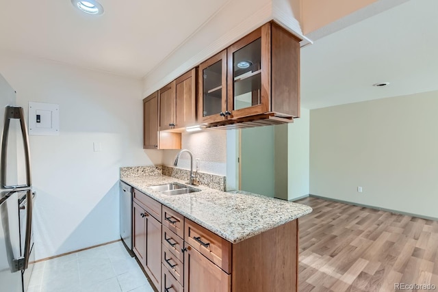 kitchen featuring light wood-type flooring, light stone countertops, sink, and stainless steel appliances