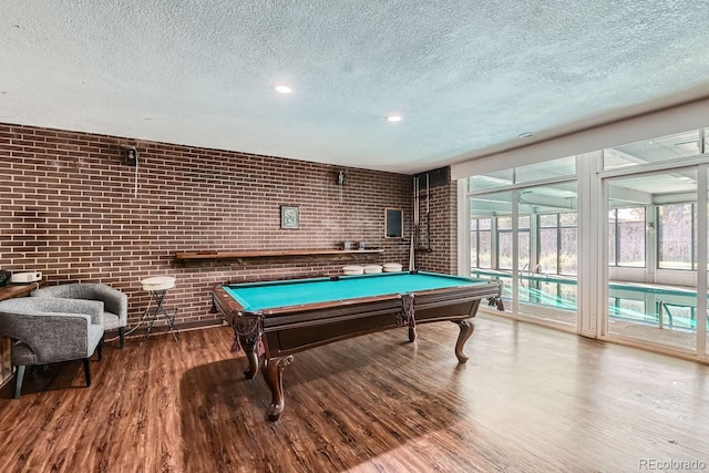 game room featuring brick wall, a textured ceiling, wood-type flooring, french doors, and pool table