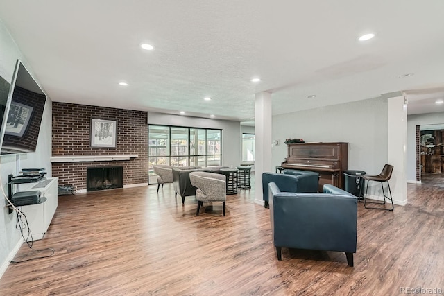 living room featuring wood-type flooring and a brick fireplace