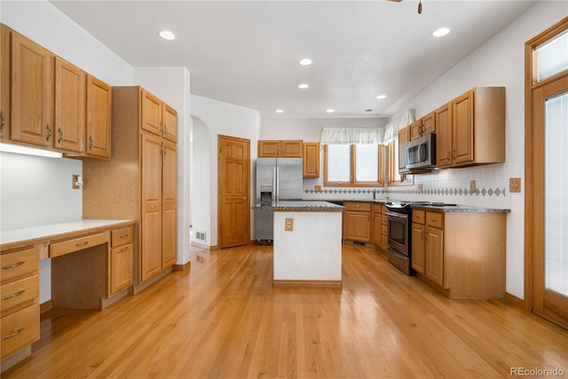 kitchen featuring light wood-type flooring, appliances with stainless steel finishes, decorative backsplash, and arched walkways