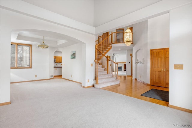 foyer entrance with arched walkways, baseboards, carpet, and stairs
