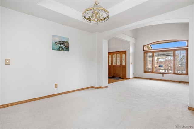 empty room featuring carpet, arched walkways, a notable chandelier, and baseboards