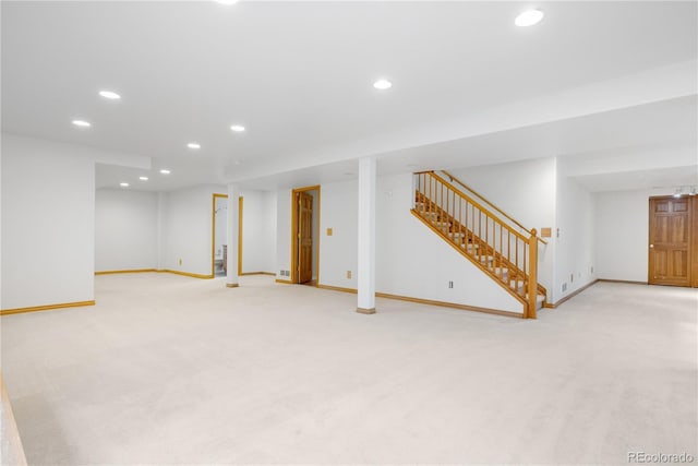 finished below grade area with stairway, baseboards, light carpet, and recessed lighting