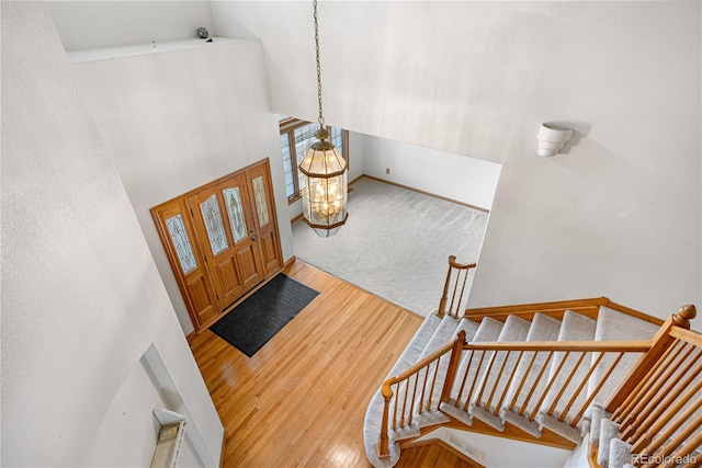entrance foyer featuring stairs, a towering ceiling, baseboards, and wood finished floors