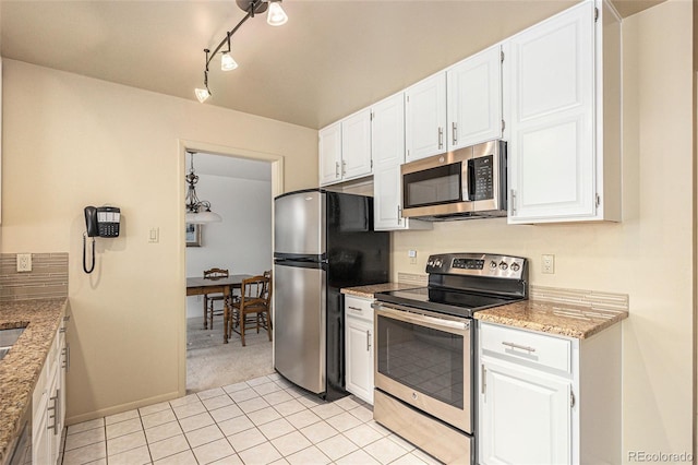 kitchen with light stone counters, light tile patterned floors, appliances with stainless steel finishes, white cabinets, and light carpet