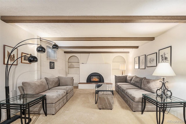 living room with a textured ceiling, beamed ceiling, a glass covered fireplace, and light colored carpet