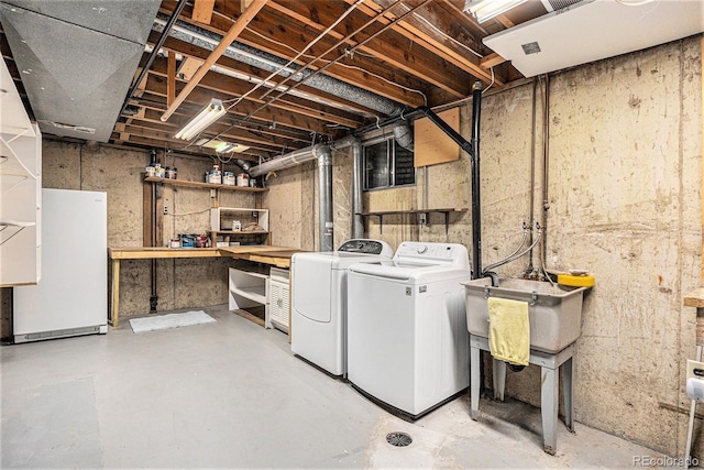 unfinished basement featuring freestanding refrigerator, independent washer and dryer, and a sink