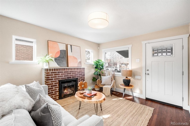 living room featuring a brick fireplace, wood finished floors, and baseboards