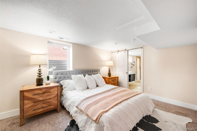 bedroom with baseboards, visible vents, a textured ceiling, a barn door, and carpet flooring