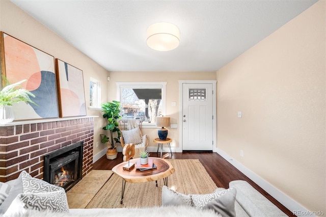 living area featuring a fireplace, baseboards, and wood finished floors