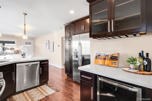 kitchen featuring dark wood-style floors, wine cooler, appliances with stainless steel finishes, light countertops, and dark brown cabinets