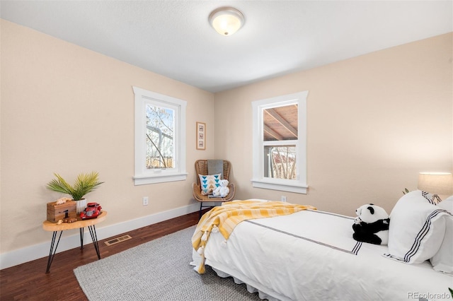 bedroom with wood finished floors, visible vents, and baseboards