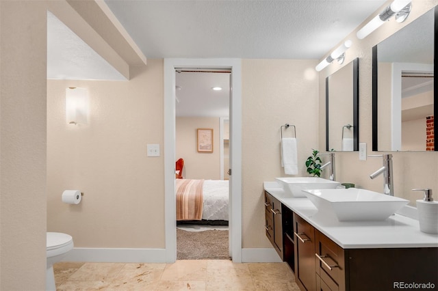 bathroom with toilet, a textured ceiling, baseboards, and a sink