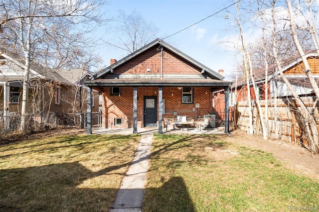 back of house featuring a yard, brick siding, and fence