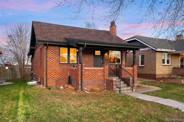 bungalow-style home with a front lawn, a porch, fence, brick siding, and a chimney