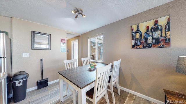 dining space featuring a textured ceiling and light hardwood / wood-style flooring