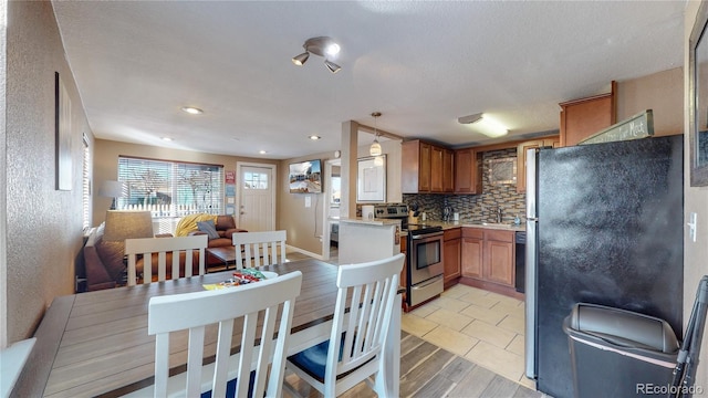 kitchen featuring appliances with stainless steel finishes, tasteful backsplash, sink, hanging light fixtures, and kitchen peninsula