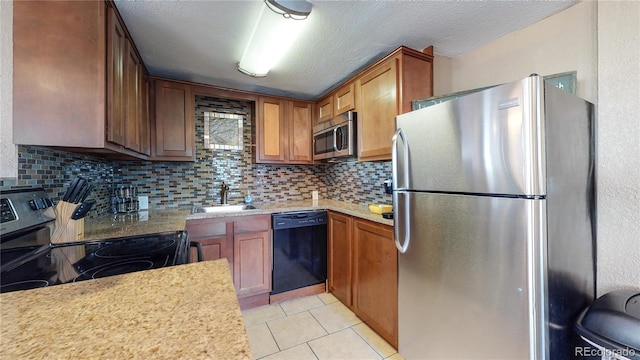 kitchen featuring sink, tasteful backsplash, a textured ceiling, light tile patterned floors, and appliances with stainless steel finishes