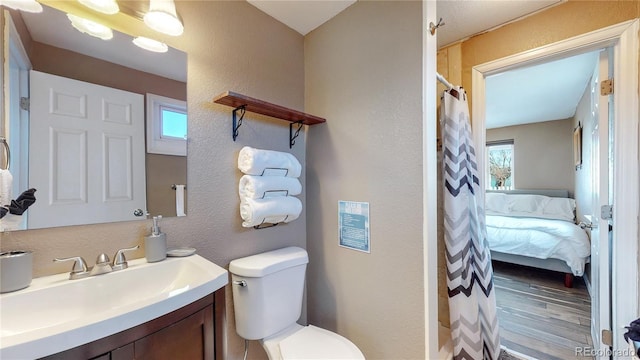 bathroom featuring vanity, a healthy amount of sunlight, hardwood / wood-style floors, and toilet