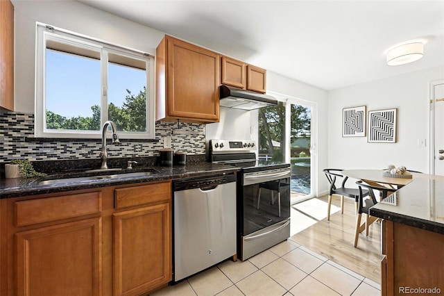 1380 Holly Dr E, Broomfield, CO 80020 - kitchen with appliances with stainless steel finishes, under cabinet range hood, brown cabinets, decorative backsplash, and light tile patterned flooring