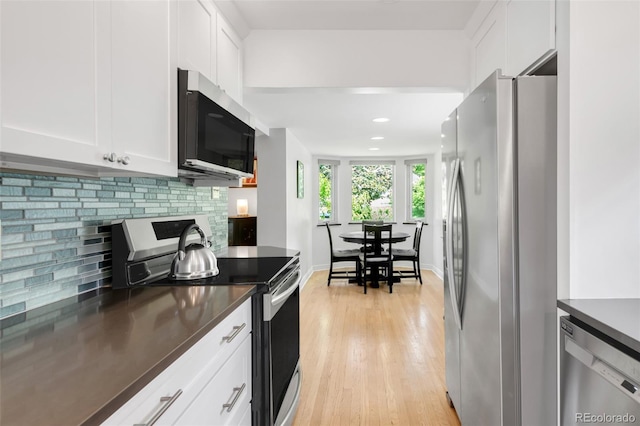 1185 Glencoe St, Denver, CO 80220 - kitchen with appliances with stainless steel finishes, dark countertops, backsplash, white cabinetry, and light wood-style floors