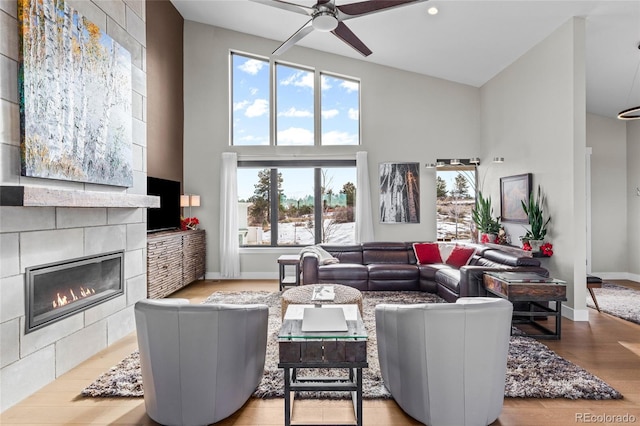 living room featuring a fireplace, light hardwood / wood-style flooring, a wealth of natural light, and ceiling fan